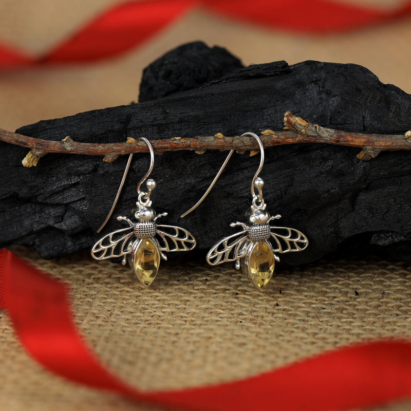 Silver bee earrings with yellow gemstones on a natural background
